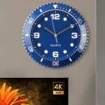 Relógio de parede com mostrador azul, números brancos e ponteiros prateados, marcando 10:10, com moldura circular e detalhes de minutos ao redor.