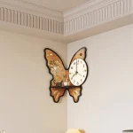 Relógio de parede em forma de borboleta com detalhes de flores e uma parte do mostrador de horas visível, colocado na parede de uma sala.