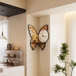 Relógio de parede com design de borboleta, detalhes em madeira e um mostrador redondo com números claros.