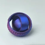 Bola de silicone roxa com superfície texturizada, vista de cima, com interior visível, sobre fundo branco.