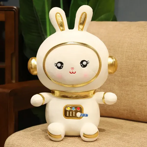 Boneco de coelho com cabeça grande, olhos grandes e brilhantes, sorriso, auriculares dourados, corpo redondo com detalhes dourados, sentado numa almofada.