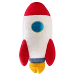 Foguete de peluche com corpo branco, detalhes vermelhos, janela azul e base amarela, ideal para decoração de ciência ou brinquedo educativo.