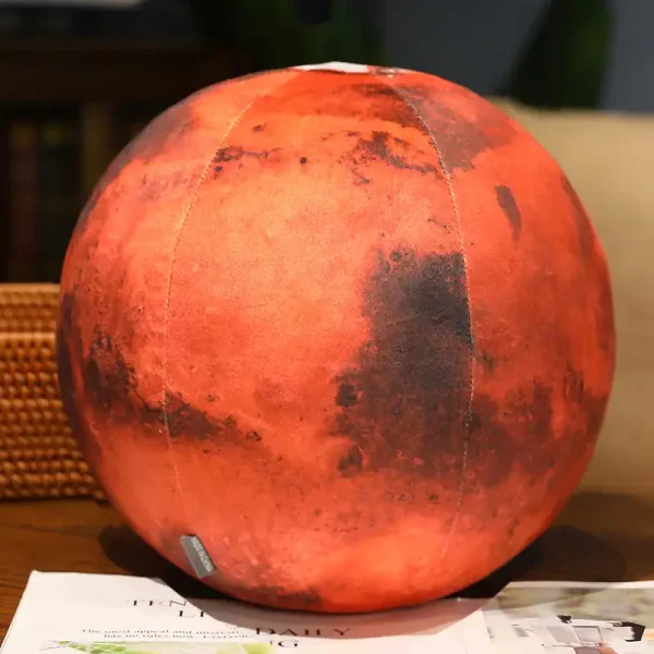Esfera de plástico com textura semelhante à superfície de Marte, com tons avermelhados e detalhes escuros, colocada sobre uma mesa de madeira.