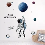 Ilustração de astronauta segurando planeta com balão, rodeado de outros corpos celestes e estrelas, com frase "I NEED MORE SPACE".