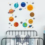 Adesivos de planetas, sol e estrelas em estilo cartoon decoram a parede acima da cama de ferro preta com almofadas de animais.