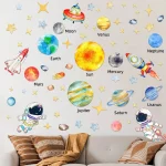 Decoração de parede com planetas do sistema solar, estrelas, astronautas e foguetes em cores vibrantes para quarto de criança.