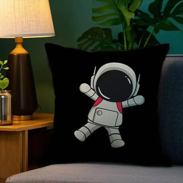 Almofada preta com desenho de astronauta sorridente com capacete e traje espacial, colocada numa cadeira junto a uma lâmpada de mesa e uma planta de folhas grandes.