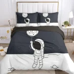 Conjunto de roupa de cama com astronauta a segurar um balão de lua, incluindo duas almofadas com astronautas e balões lunares, em cores preto e branco.
