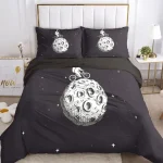 Conjunto de roupa de cama preto com desenhos de lua, astronauta e estrelas, incluindo duas almofadas com imagens da lua.