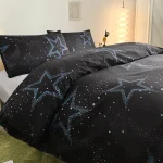 Conjunto de roupa de cama preto com estrelas azuis e galáxias, incluindo cobertor e fronhas, decorando um quarto moderno com iluminação suave e lâmpada de pé.