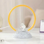 Lâmpada de plasma com anel de luz amarelo e figura de astronauta a pedalar uma bicicleta, sobre base decorativa com símbolos lunares e estrelas.