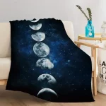 Manta de sofá com padrão de fases da lua, de cores escuras e detalhes de estrelas, colocada sobre um sofá branco na sala de estar.
