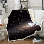 Manta decorativa com imagem de galáxia e estrelas, colocada sobre um sofá branco com almofadas, numa sala moderna com prateleira de livros ao fundo.