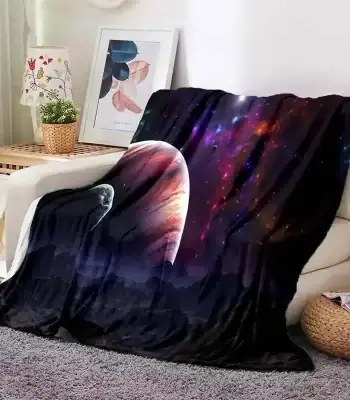Manta de sofá com design de galáxia, estrelas e planetas, colocada sobre um sofá branco na sala de estar.