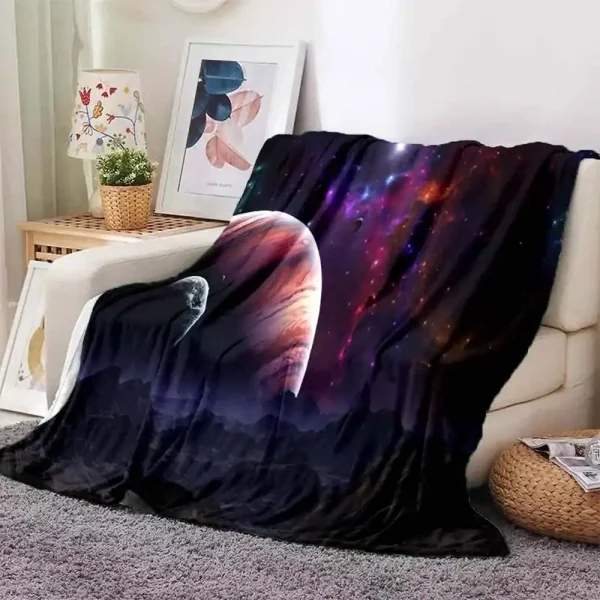Manta de sofá com design de galáxia, estrelas e planetas, colocada sobre um sofá branco na sala de estar.