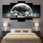 Quadro de cinco painéis com imagem da lua cheia e nuvens, decorando uma parede de quarto com cama e abajures.