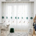 Cortina de tecido branco com desenhos de planetas, estrelas e foguetes coloridos, decorando uma janela de quarto infantil.