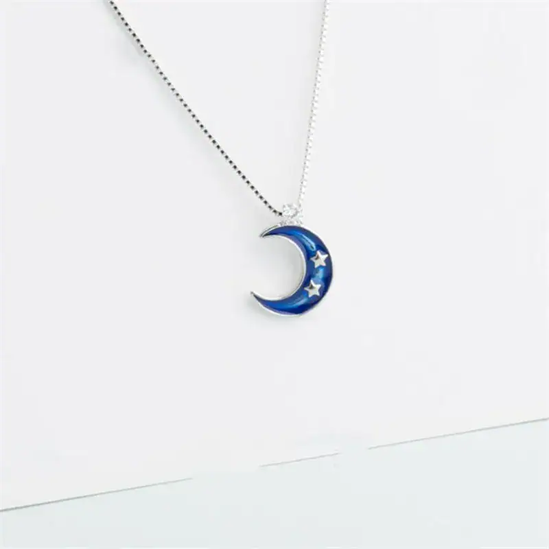 Lune étoilée en pendentif Pendentif en forme de lune bleue avec étoiles, suspendu à une chaîne fine.