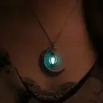 Pendentif lune en métal avec lanterne suspendue, illuminée d'une lumière bleue, porté autour du cou.