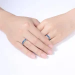 Duas mãos usando anéis de aço inoxidável com motivos científicos, simbolizando o amor e a paixão pela ciência.