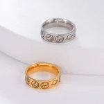 Dois anéis de metal, um prateado e um dourado, com símbolos científicos gravados, colocados sobre uma superfície branca.