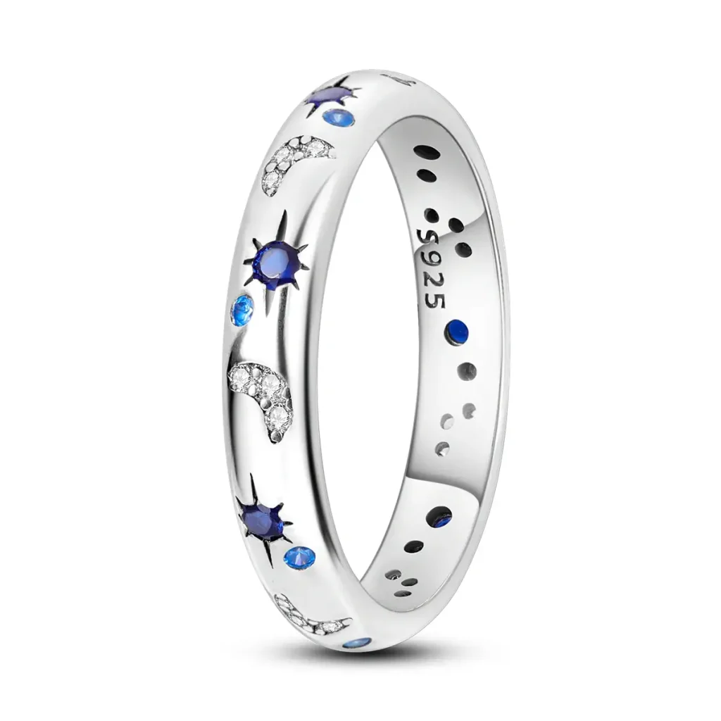 Anel de prata com detalhes de estrelas azuis, cristais e desenhos lunares, vista frontal, com detalhes brilhantes e acabamento polido.
