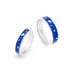 Dois anéis de prata com detalhes em azul, decorados com estrelas, planetas e outros elementos do espaço, vistos de diferentes ângulos.