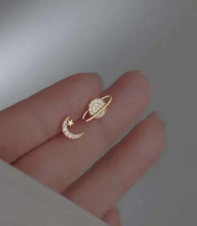 Joia de orelha em forma de lua e estrela adornada com diamantes, simbolizando a celestialidade e a elegância.