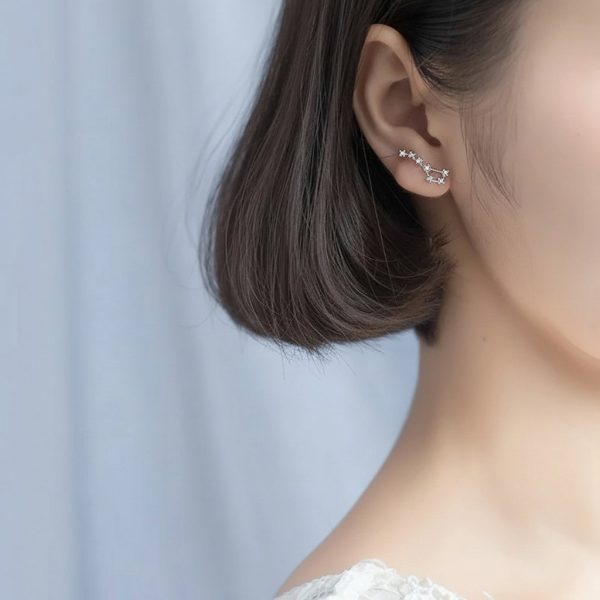Pingente em forma de constelação estrelada, em prata esterlina, usado na orelha de uma mulher.