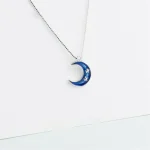 Pingente em forma de lua azul com estrelas, suspenso em uma corrente fina.