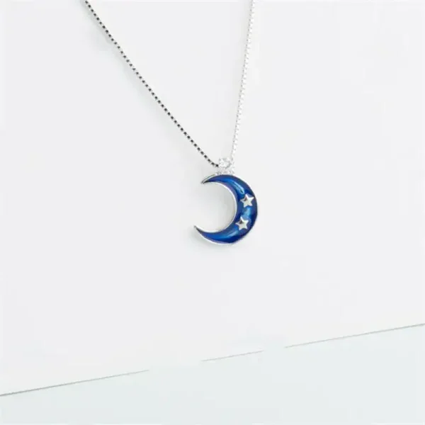 Pingente em forma de lua azul com estrelas, suspenso em uma corrente fina.