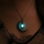 Pingente de lua em metal com lanterna suspensa, iluminada por uma luz azul, usado ao redor do pescoço.