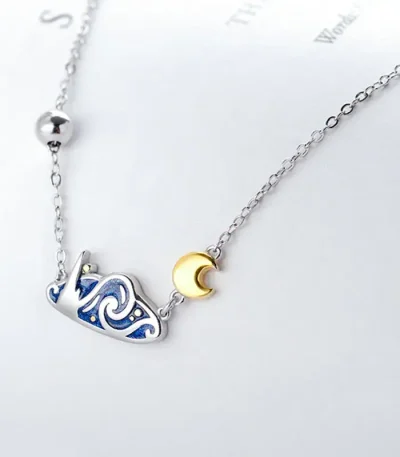 Colar delicado com pingente de lua em ouro e constelação em prata, perfeito para amantes de astronomia e ciências.