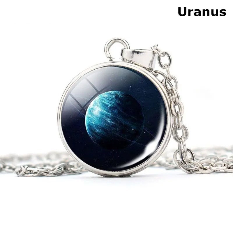 Pingente em metal com imagem do planeta Urano, representando um corpo celeste azul e gelado, suspenso em uma corrente de metal prateado.