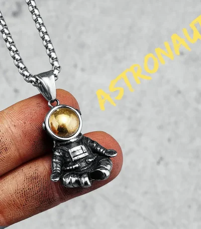 Colar com pingente de astronauta em metal prateado e bola dourada, inspirado no espaço e na exploração espacial.