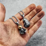 Pingentes de astronautas em metal prateado, suspensos em uma corrente, colocados sobre uma mão suja. Ideal para amantes de ciência e astronomia.