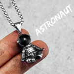Pingente de astronauta em metal com bola preta, suspenso em uma corrente de aço inoxidável, ideal para amantes de astronomia e ciência.