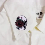 Patch de astronauta com rosto soviético numa peça de roupa branca, símbolo da exploração espacial e da história soviética.