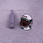 Pen USB cinza ao lado de um distintivo representando um astronauta soviético com capacete e logotipo CCCP.