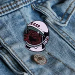 Broche de metal com logotipo soviético representando um urso em traje de astronauta, colocado em uma jaqueta de denim. Acessório original para os amantes de ciência e história espacial soviética.