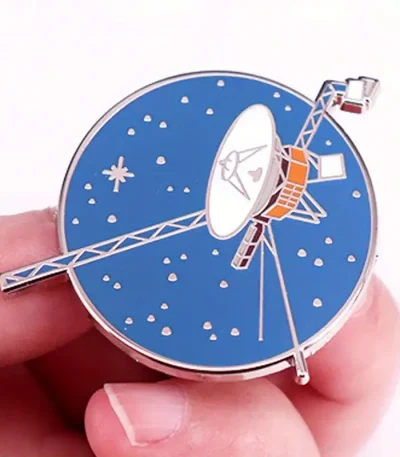 Relógio decorativo em forma de satélite com mostrador azul e detalhes metálicos.