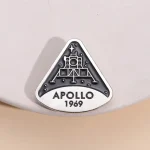 Uma broche ou badge representando a missão Apollo 11 da NASA, com a data 1969, símbolo emblemático da exploração espacial.