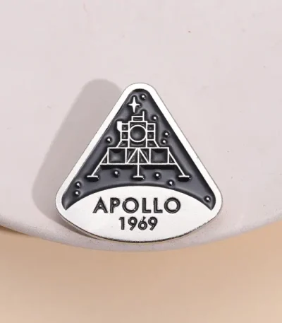 Uma broche ou badge representando a missão Apollo 11 da NASA, com a data 1969, símbolo emblemático da exploração espacial.