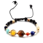 Pulseira com contas de diferentes cores e tamanhos, incluindo uma grande conta marrom, uma azul, uma vermelha e uma amarela, com fechos dourados e cordão ajustável.