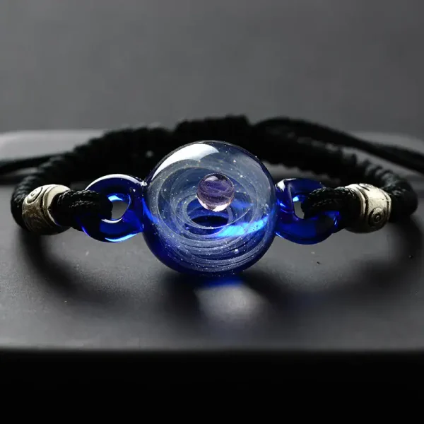 Pulseira de cordão negro com esfera de vidro azul e detalhes metálicos.