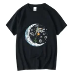 T-shirt preta com ilustração de um astronauta flutuando no espaço, rodeado de planetas, estrelas e uma lua brilhante, perfeita para os amantes de ciência e astronomia.