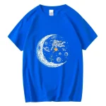 T-shirt azul com um padrão de astronauta flutuando no espaço, rodeado de planetas, estrelas e uma lua estilizada. Perfeito para os amantes de ciência e astronomia.