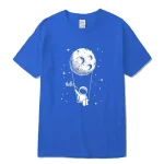 Camiseta azul com ilustração de um astronauta pendurado na lua, cercado por estrelas, com a palavra "Hello" escrita ao lado. Design lúdico e científico para os amantes do espaço.