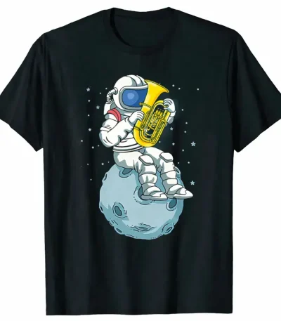 T-shirt preta com um astronauta em traje tocando saxofone numa pequena lua, rodeado de estrelas, design divertido e original para os amantes de ciência e música.