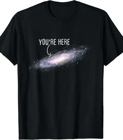 T-shirt galáxia com texto "You're Here" em branco sobre fundo preto, representando uma galáxia espiral com uma mensagem humorística e cósmica.
